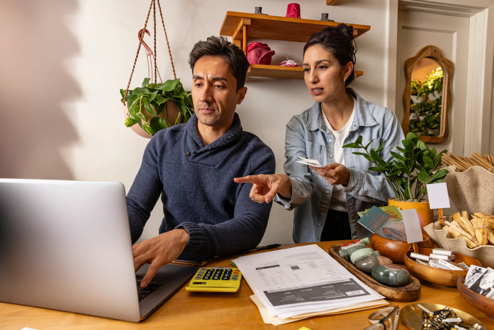 Two business owners reviewing paperwork together at a laptop
